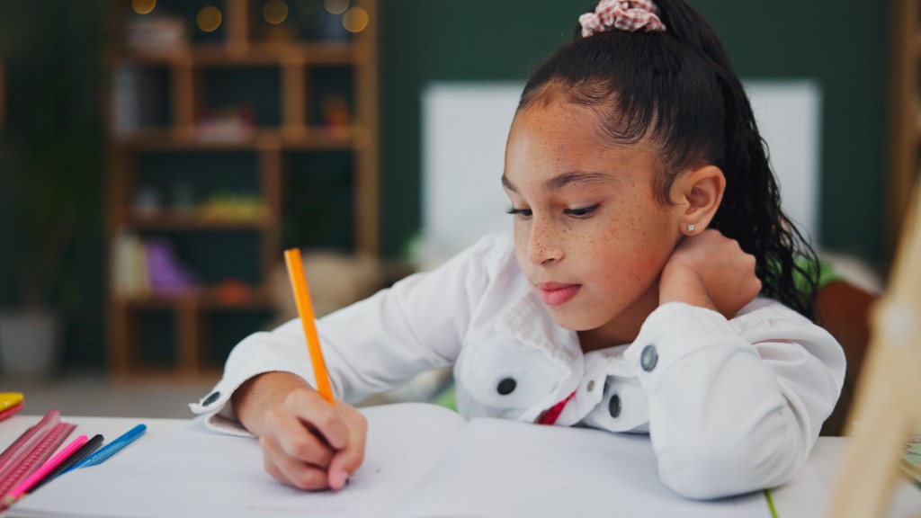 A young girl resting her head on her hand while writing in a notebook with an orange pencil at a white desk