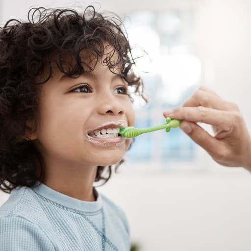 Child getting help brushing their teeth
