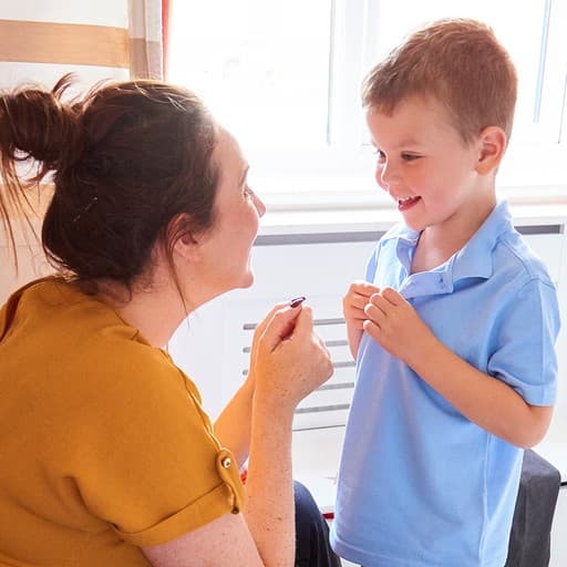 Child practicing buttoning a shirt with supportive guidance