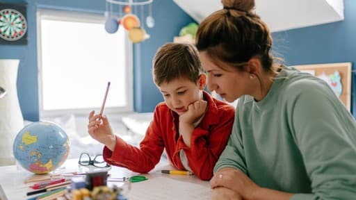 Adult supporting a child with homework at a desk