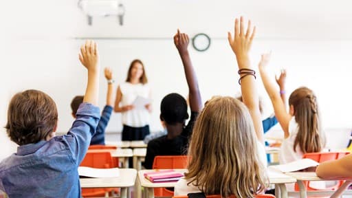 Students raising their hands in a classroom