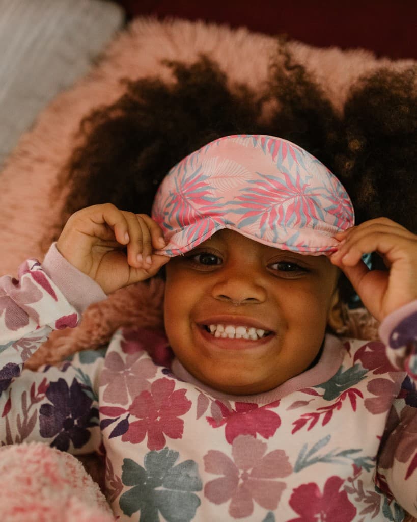Child smiling while lifting a sleep mask